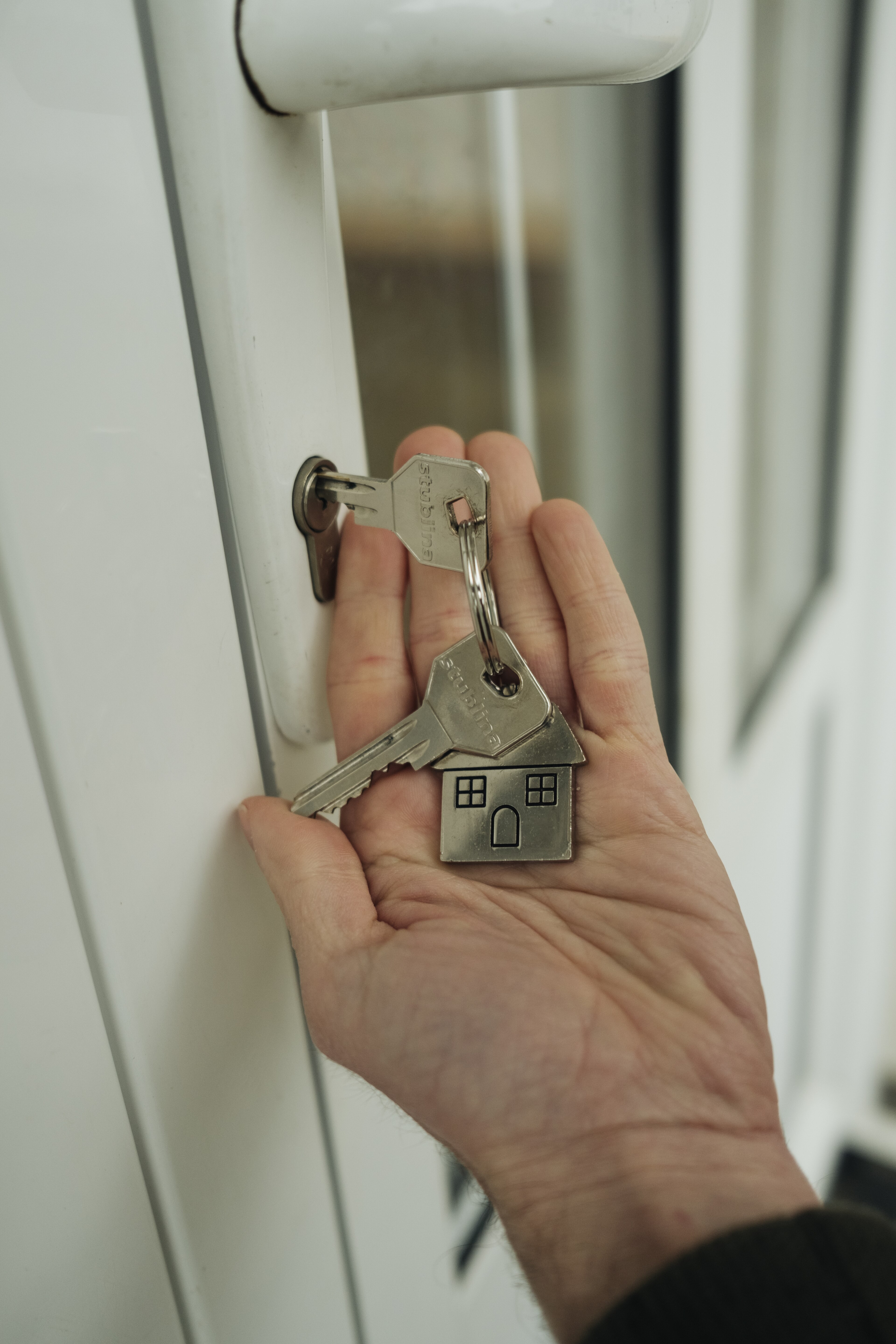 Hand holding house keys near a door lock / 手持房屋钥匙准备开门